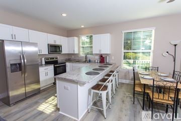 Pensacola house for rent - A kitchen with white cabinets and a granite countertop.