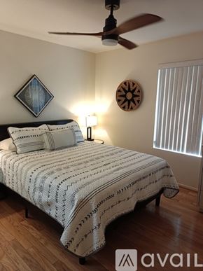 Surprise house for rent - A bedroom with a bed, a ceiling fan, and a wall clock.