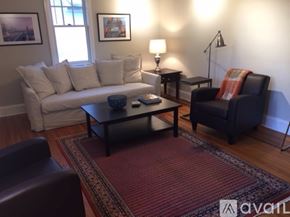 Charlotte townhouse for rent - A living room with a white couch, a black chair, and a red rug.
