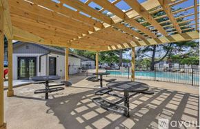 Nashville townhouse for rent - A wooden pergola over a patio with tables and a pool in the background.