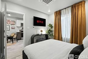 Dallas apartment for rent - A bedroom with a large bed, a nightstand with a lamp, and a wall with a city skyline mural.