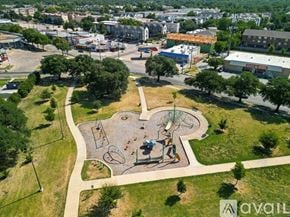 Dallas apartment for rent - A playground with a slide, swings, and a seesaw is surrounded by trees and grass.