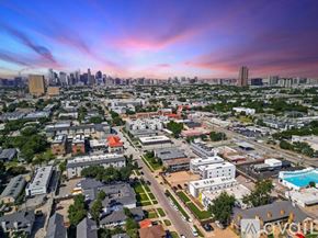 Dallas apartment for rent - A cityscape with buildings and a swimming pool in the foreground.