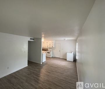 Lynchburg house for rent - A spacious room with wood flooring and a kitchen area in the background.