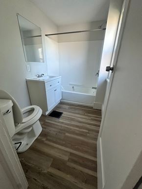 Lorain apartment for rent - A white bathroom with wood flooring and a white toilet.