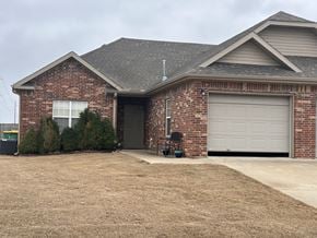 Centerton house for rent - A brick house with a grey garage door.