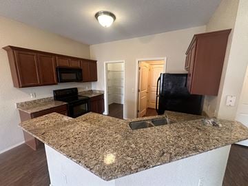 Centerton house for rent - A kitchen with granite countertops and wooden cabinets.