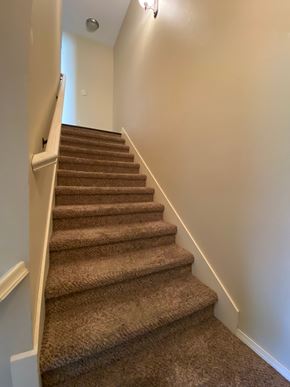 Centerton house for rent - A staircase with a carpeted runner and white handrails.