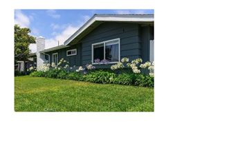 Huntington Beach apartment for rent - A house with a blue exterior and white trim is surrounded by a well-kept lawn and flowering plants.