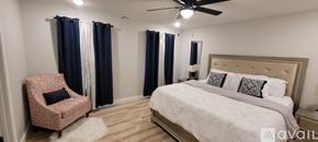 Joplin townhouse for rent - A bedroom with a large bed and a chair with a floral pattern.