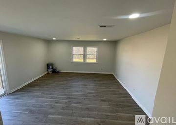 Greensboro house for rent - A spacious room with wooden flooring and a window.