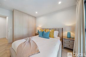 Beverly Hills house for rent - A bedroom with a large bed, a nightstand with a lamp, and a window with curtains.