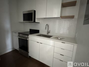 Cambridge apartment for rent - A kitchen with white cabinets and a black microwave.