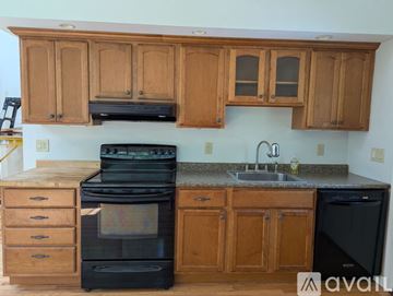 York apartment for rent - A kitchen with wooden cabinets and black appliances.