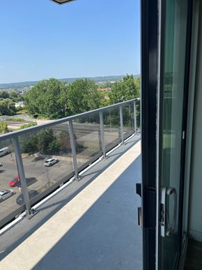 Burlington apartment for rent - A balcony with a view of a parking lot and trees.