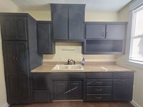Pensacola house for rent - A kitchen with black cabinets and a granite countertop.