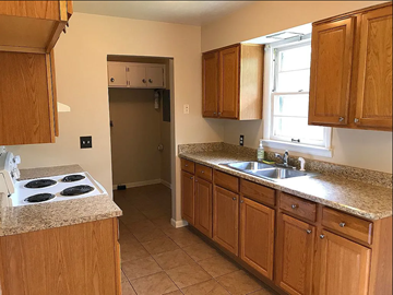 Lima house for rent - A kitchen with wooden cabinets and a granite countertop.