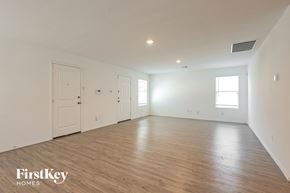 New Braunfels house for rent - A spacious room with wooden flooring and white walls, with a door on the left and two windows on the right.
