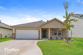 Conroe house for rent - A house with a garage door and a tree in front.