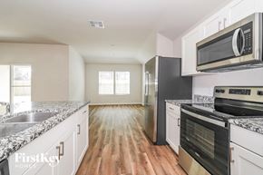 Conroe house for rent - A kitchen with a stove top oven and a microwave above it.
