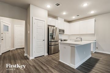 Shenandoah house for rent - A kitchen with white cabinets and a stainless steel refrigerator.