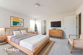 Conroe house for rent - A bedroom with a large bed, a chair, and a painting on the wall.