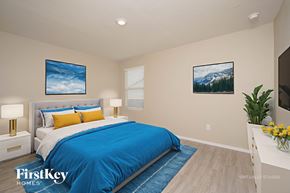New Braunfels house for rent - A bedroom with a blue bedspread and a painting of a mountain scene on the wall.