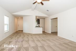 Magnolia house for rent - A spacious, empty room with a fan and carpeted floor.