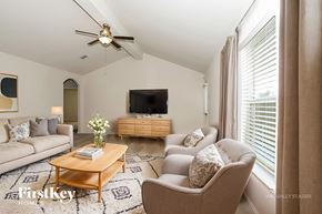 Magnolia house for rent - A living room with a television, a couch, a coffee table, and a ceiling fan.