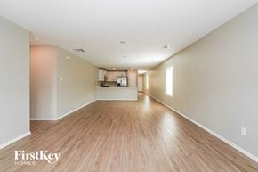 Baytown house for rent - A spacious room with wooden floors and a kitchen area in the distance.