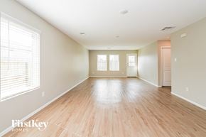 Baytown house for rent - A spacious room with wooden floors and a large window on the left side.
