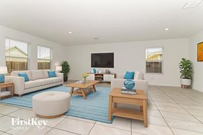 Princeton house for rent - A living room with a white couch, a white chair, a white ottoman, a wooden coffee table, a blue rug, a flat screen TV, and a potted plant.