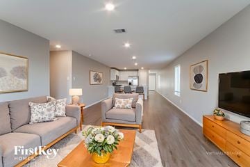 Baytown house for rent - A living room with a grey couch, a coffee table with flowers, and a flat screen TV.