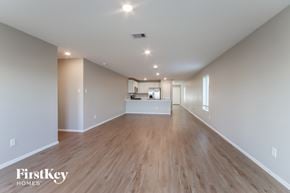 Baytown house for rent - A spacious room with wooden floors and a kitchen area in the background.