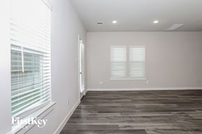 Shenandoah house for rent - A room with wooden flooring and two windows with blinds.