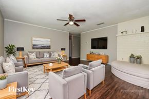 Rockwall house for rent - A living room with a grey couch, a coffee table, and a flat screen TV mounted on the wall.