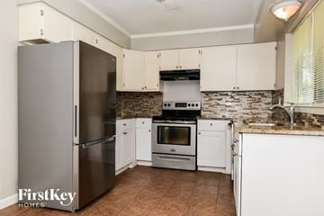 Rockwall house for rent - A kitchen with a refrigerator, oven, and cabinets.