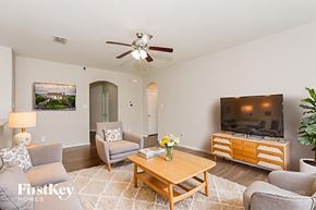 Dallas house for rent - A living room with a grey couch, a wooden coffee table, a flat screen TV and a ceiling fan.