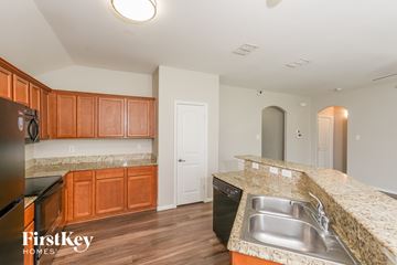 Dallas house for rent - A kitchen with wooden cabinets and a black fridge.