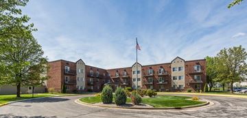 West Lafayette apartment for rent - A large brick building with a flag on top and a roundabout in front.