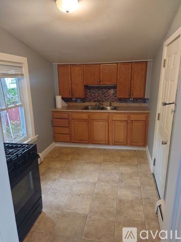 Woonsocket apartment for rent - A kitchen with wooden cabinets and a black oven.