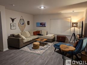New Bern house for rent - A living room with a grey sofa, a wooden coffee table, and a blue chair.