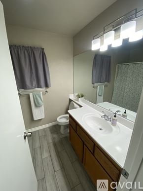 Moreno Valley house for rent - A bathroom with a large mirror, two sinks, and a window with curtains.