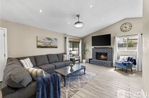 Moreno Valley house for rent - A living room with a grey sofa, a fireplace, and a TV mounted on the wall.