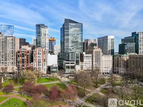 Boston apartment for rent - A cityscape with a mix of modern and older buildings, a park with trees, and a clear sky.