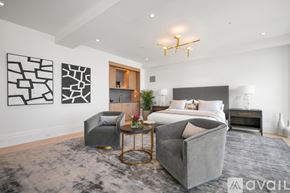 Boston apartment for rent - A modern bedroom with a large bed, grey armchair, and a coffee table with a plant on it.