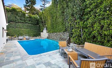 Los Angeles house for rent - A living room with a large painting on the wall and a view of a patio through the glass doors.