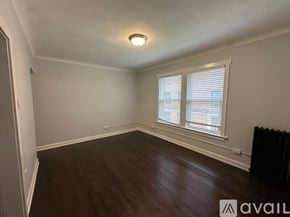 Chicago apartment for rent - A room with wooden floors and a window with blinds.