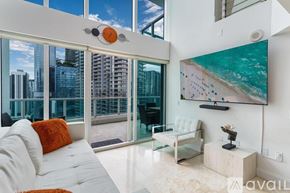 Miami condo for rent - A living room with a large window overlooking a cityscape.