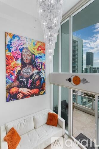 Miami condo for rent - A modern living room with a large painting on the wall and a chandelier hanging from the ceiling.